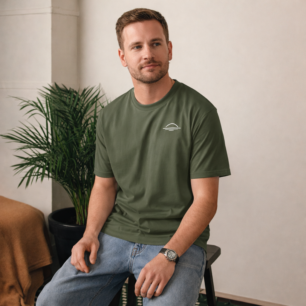 A man sitting down wearing an organic cotton khaki green t-shirt.