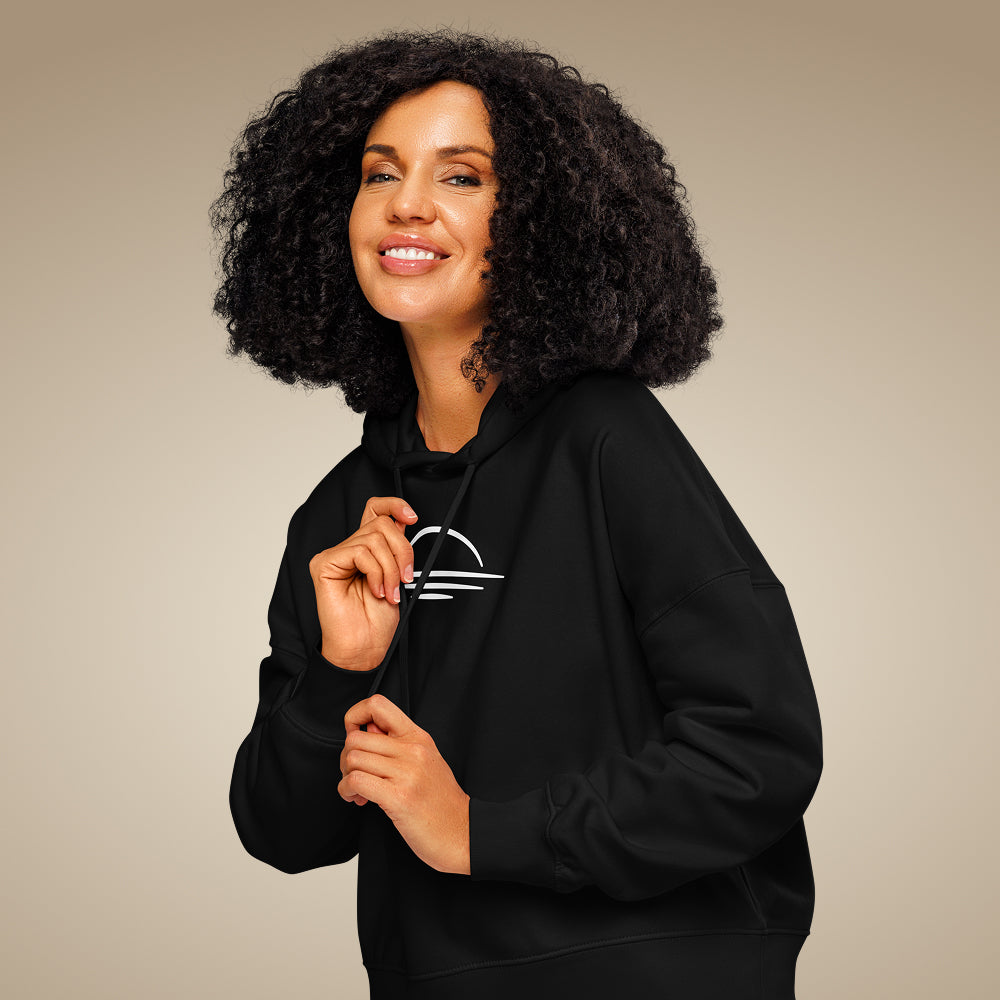 Women’s organic cotton hoodie jumper in black with minimal chest logo, worn by model