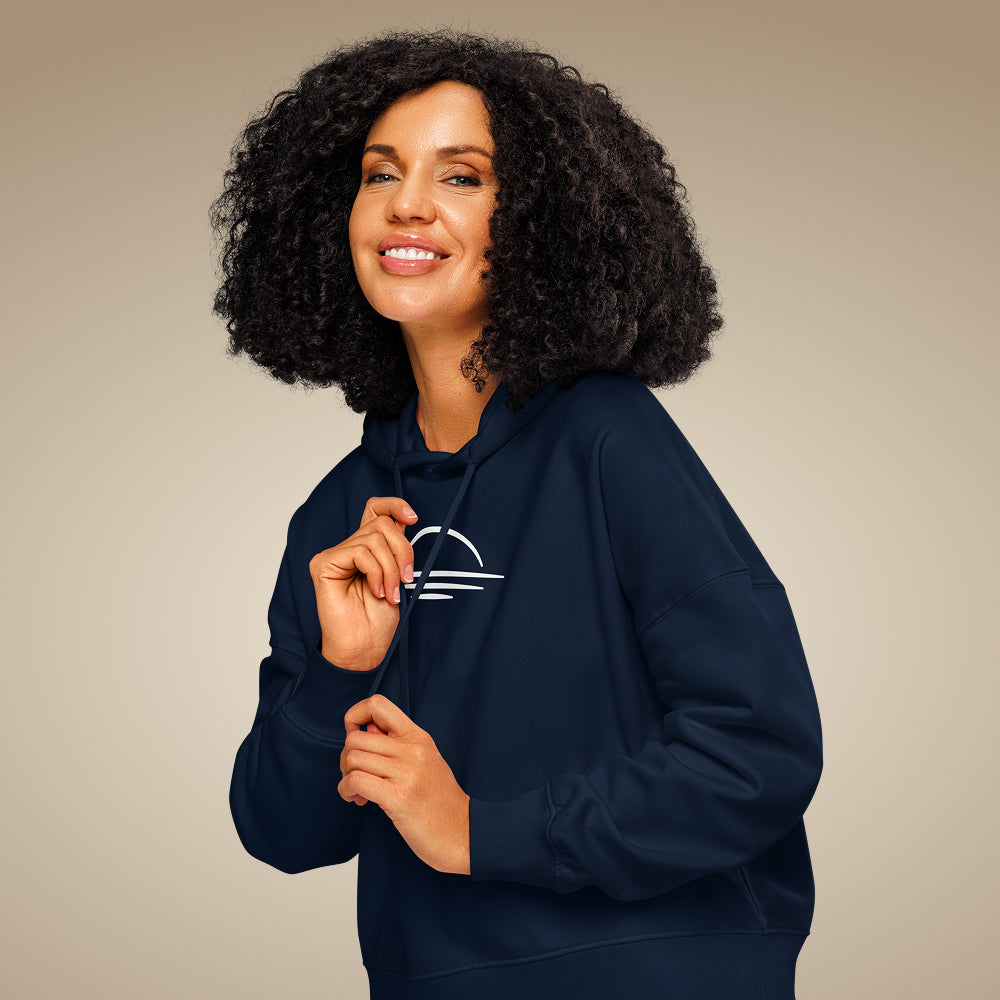 Women’s organic cotton hoodie jumper in french navy with minimal chest logo, worn by model