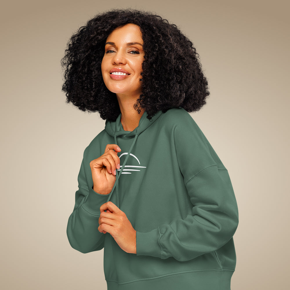 Women’s organic cotton hoodie jumper in green bay with minimal chest logo, worn by model