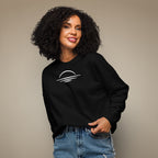 Woman wearing a black sweatshirt with a sunset emblem on a beige studio background