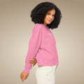 Woman wearing an organic pink cotton sweatshirt with a logo on a beige background