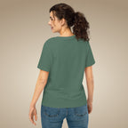 Woman wearing a green t-shirt and blue jeans against a beige background