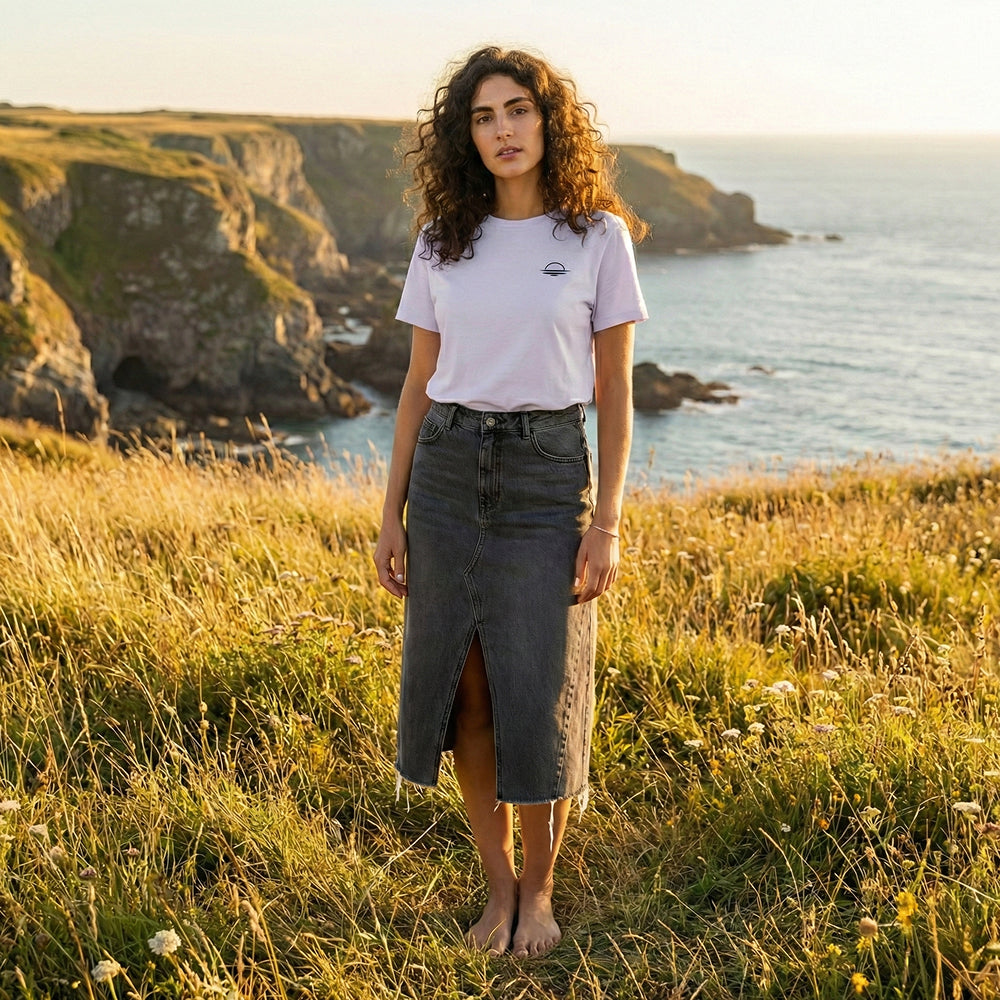 A woman stood grounding and barefoot in nature wearing an organic cotton t-shirt in lavender.